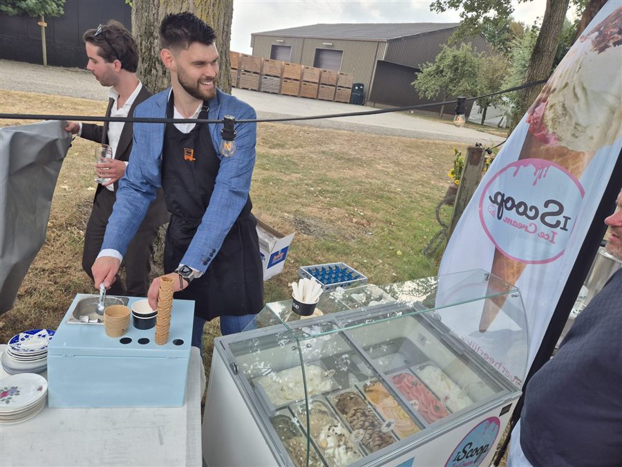 IJscoman van iScoop bereidt een ijshoorntje bij de schepijsvitrine