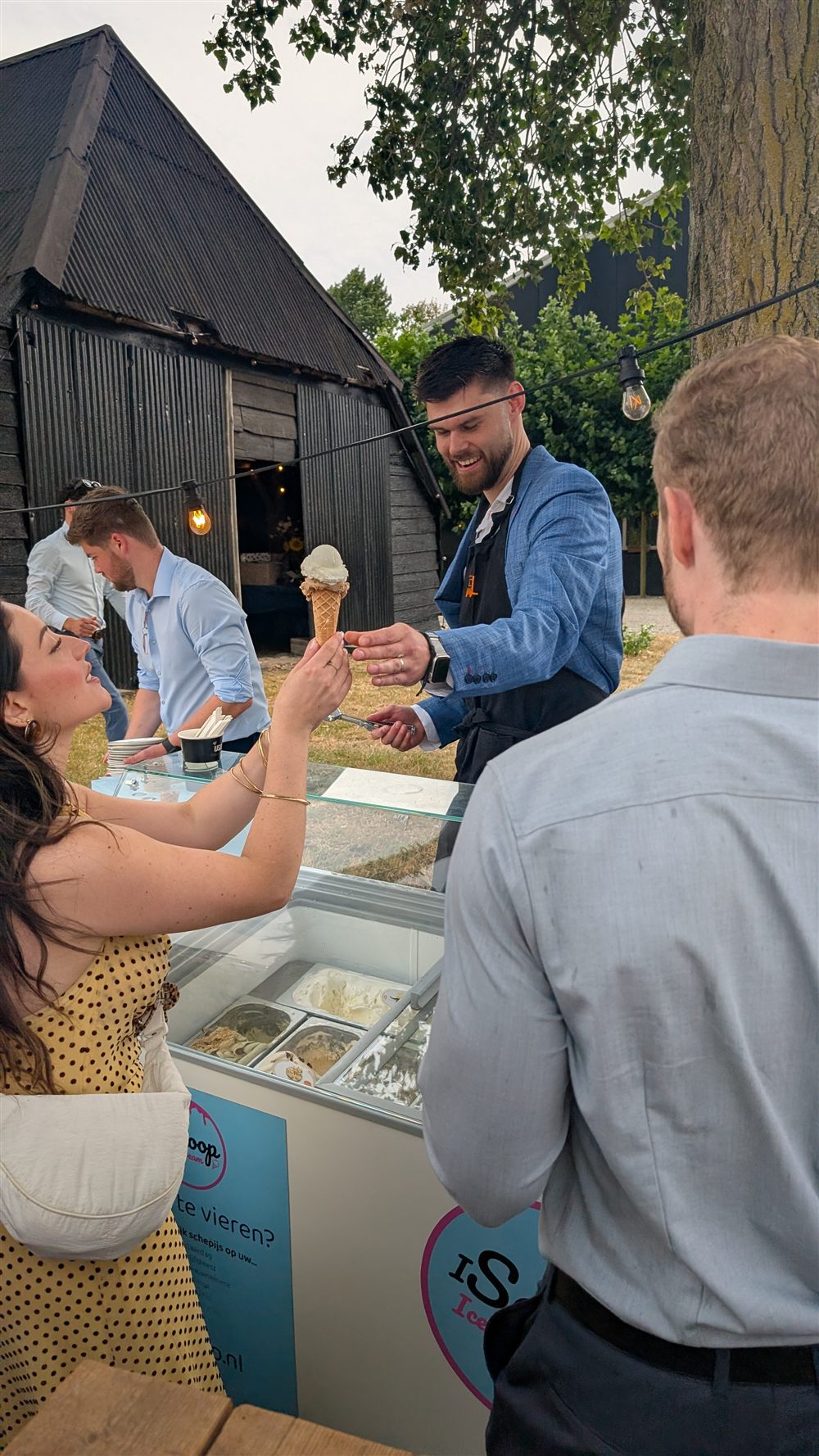 IJscoman van iScoop overhandigt een ijshoorntje aan een gast
